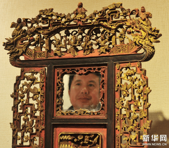（2）2月9日，一位市民在觀看一個(gè)工藝繁復(fù)的帶鏡木雕盆架。