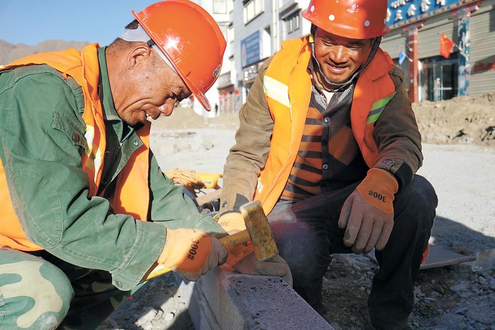 節(jié)日期間，日喀則市主城區(qū)道路硬化項(xiàng)目工地上依舊熱火朝天，來(lái)自甘肅的兩位師傅在修建路基。記者 張斌 攝