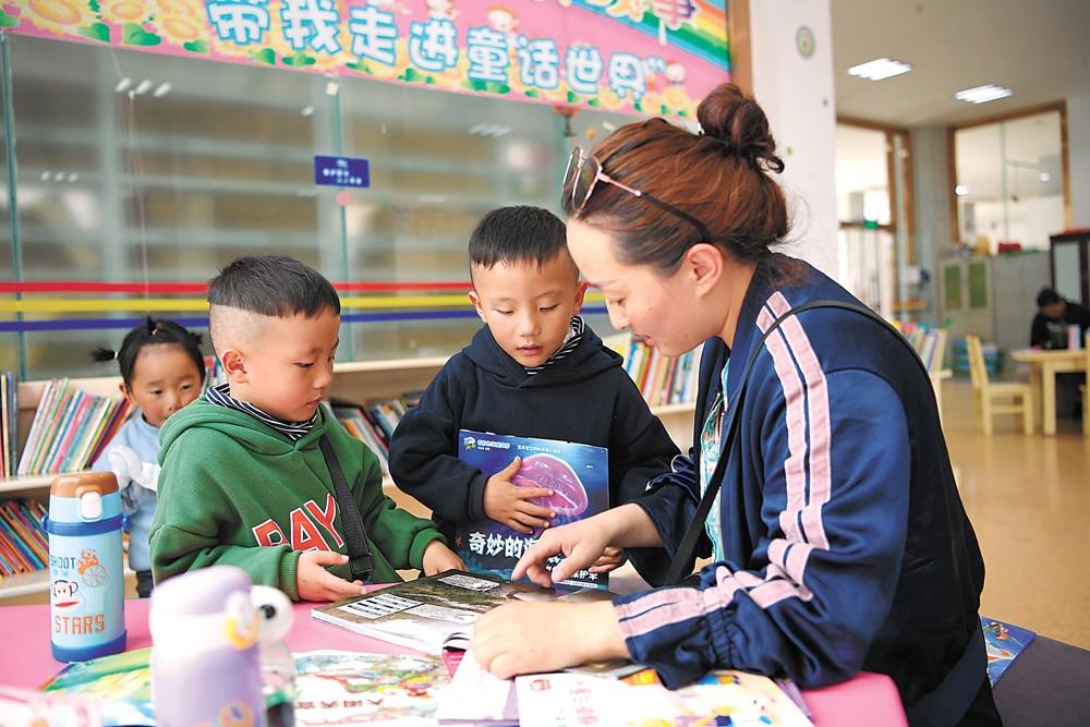 “五一”假期，一位家長(zhǎng)在圖書(shū)館親子閱讀區(qū)給孩子們講故事。