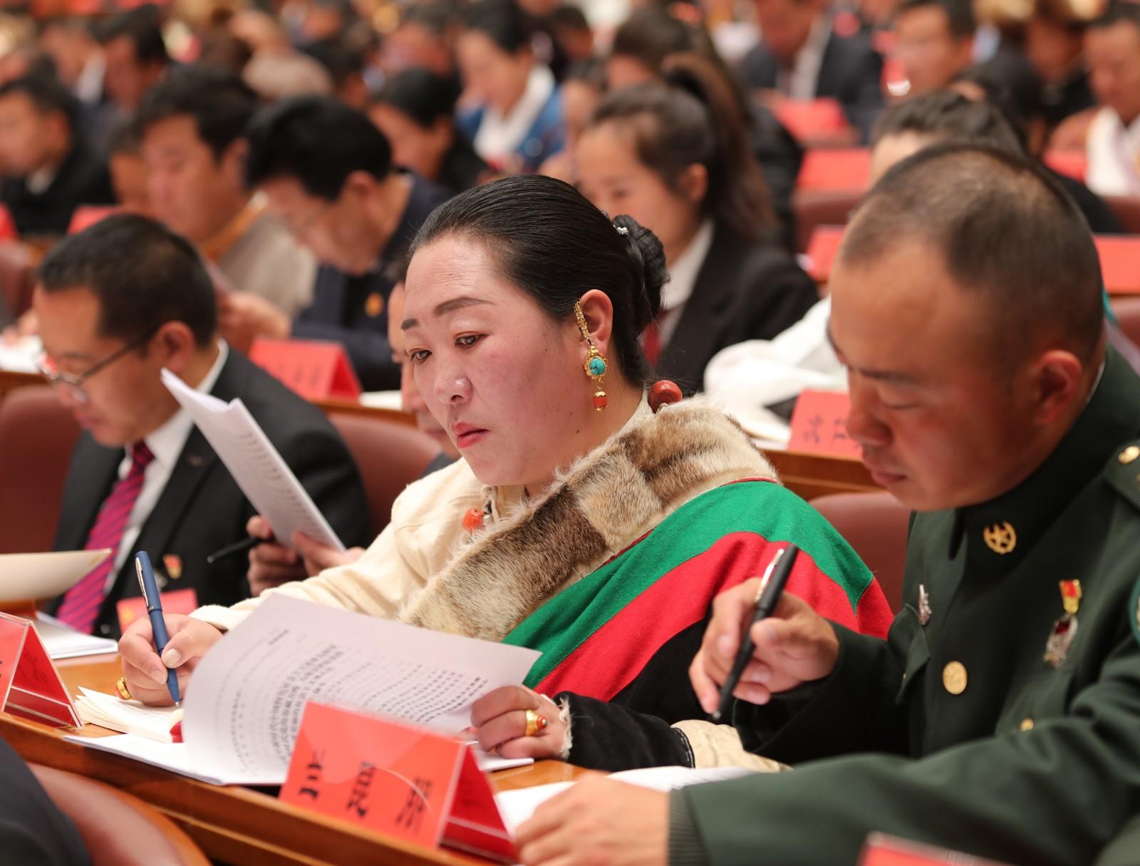 讓我們更加緊密地團(tuán)結(jié)在以習(xí)近平同志為核心的黨中央周圍，堅(jiān)持以習(xí)近平新時(shí)代中國特色社會主義思想為指導(dǎo)，全面貫徹新時(shí)代黨的治藏方略，不忘初心、牢記使命，腳踏實(shí)地、艱苦奮斗，為譜寫雪域高原長治久安和高質(zhì)量發(fā)展新篇章、建設(shè)團(tuán)結(jié)富裕文明和諧美麗的社會主義現(xiàn)代化新西藏而不懈努力奮斗，以優(yōu)異成績迎接黨的二十大勝利召開。圖為黨代表在認(rèn)真閱讀報(bào)告。